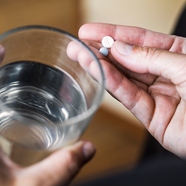 Glass of Water with Pills in Hand