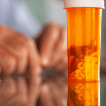 hands on table with pill bottle