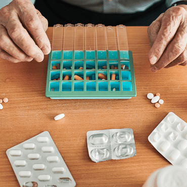 Hands placing pills in pill organizer